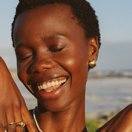 Happy woman wearing gold earrings on the beach