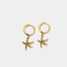 Load image into Gallery viewer, A pair of gold-filled hoop earrings with a sea star charm attached in the center.